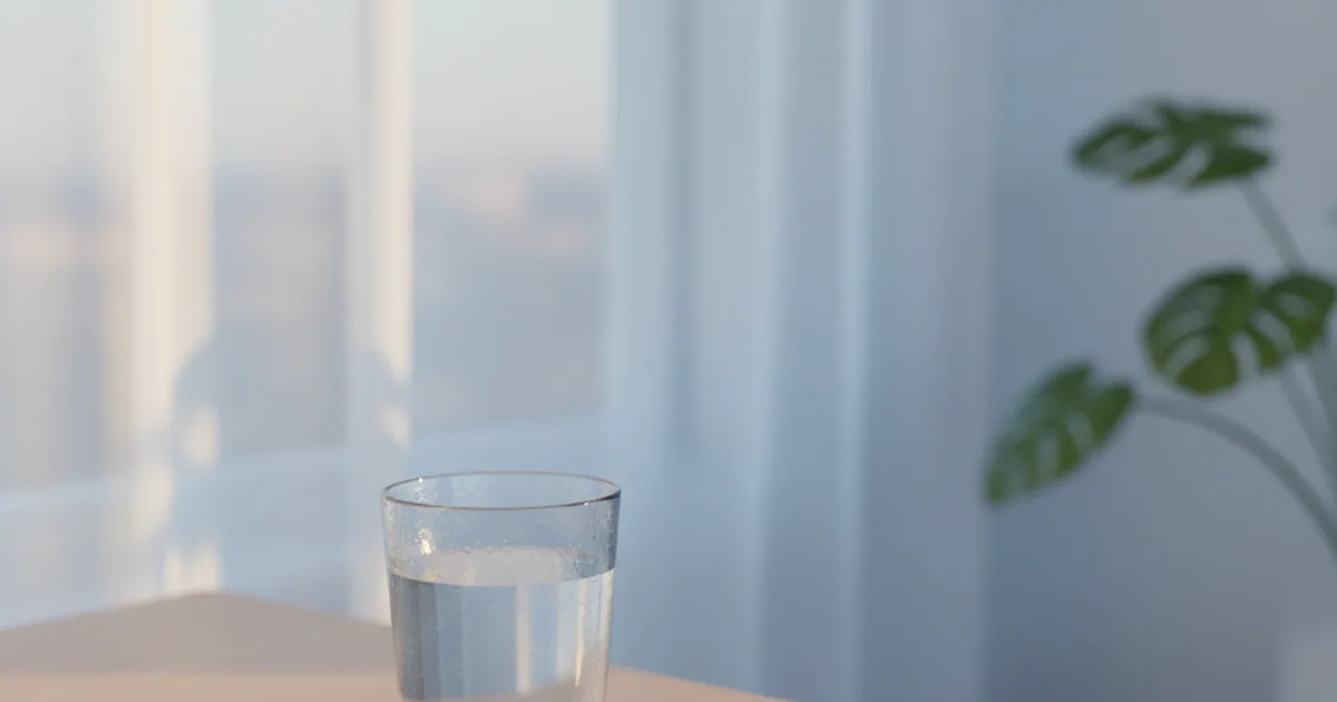 A bedside table with a phone and a glass of water in low evening light, calm mood